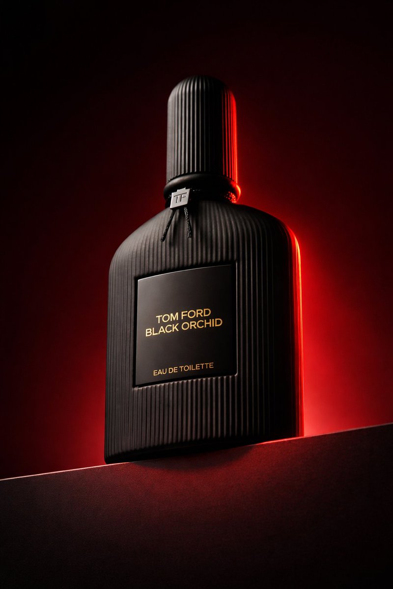 Low angle luxury product photography of a black ribbed glass perfume bottle placed on a dark horizo…