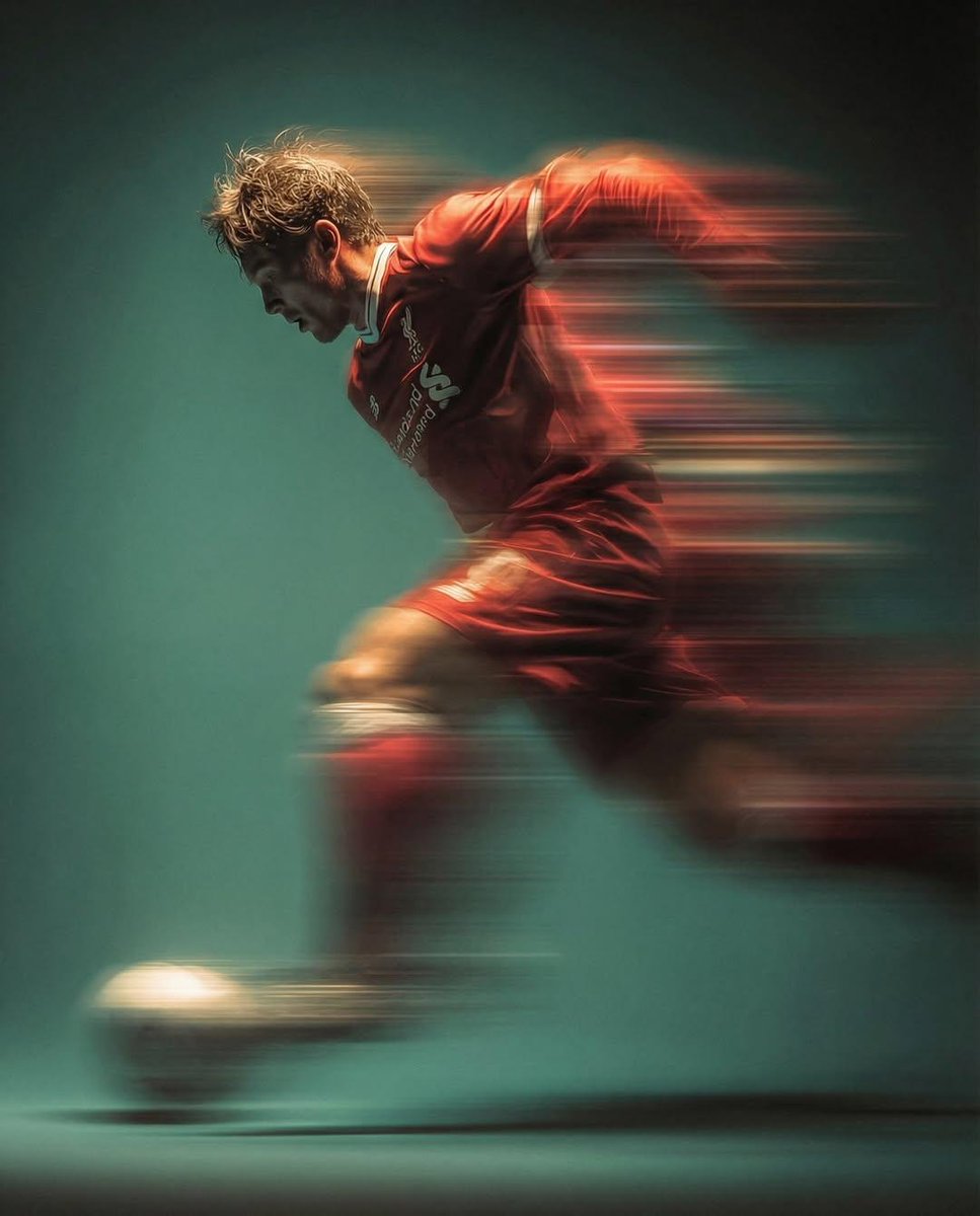 Panning shot of a mysterious soccer player in red proffesional soccer jearsy mid air kicking a ball…
